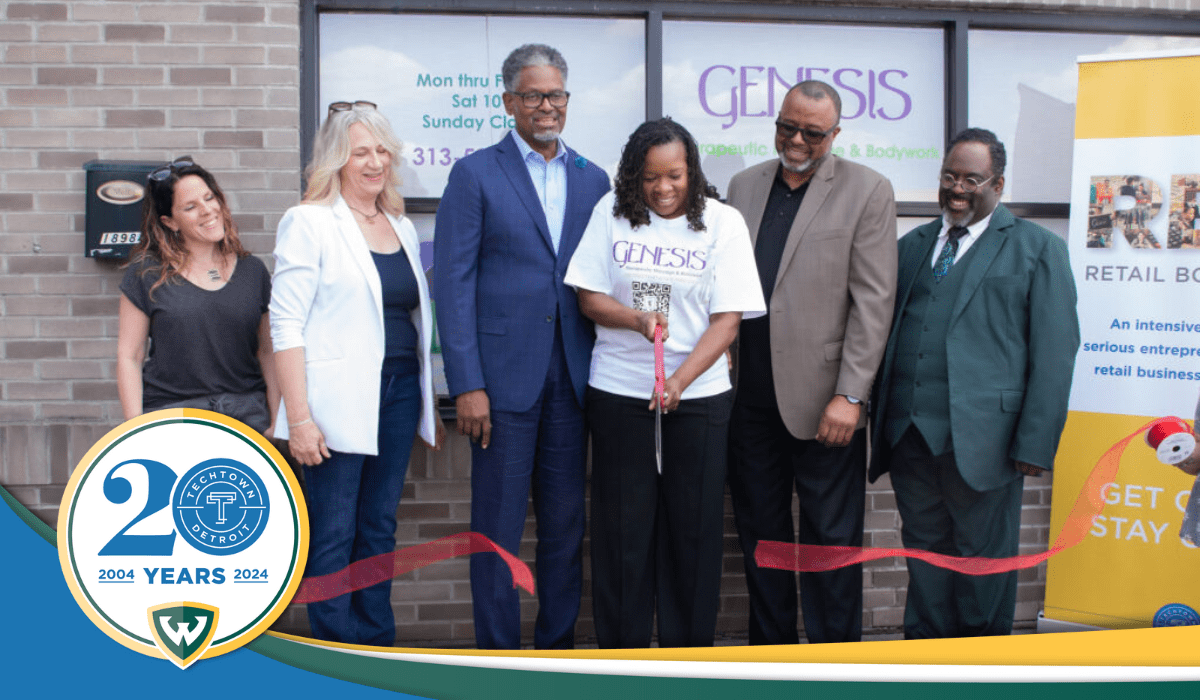 A photo of several people standing outside the new location for Genesis Therapeutic Massage and Bodywork, they stand behind a large ribbon and the person in the middle has cut the ribbon with a large pair of scissors. Overlapping this photo is TechTown Detroit's 20th anniversary logo