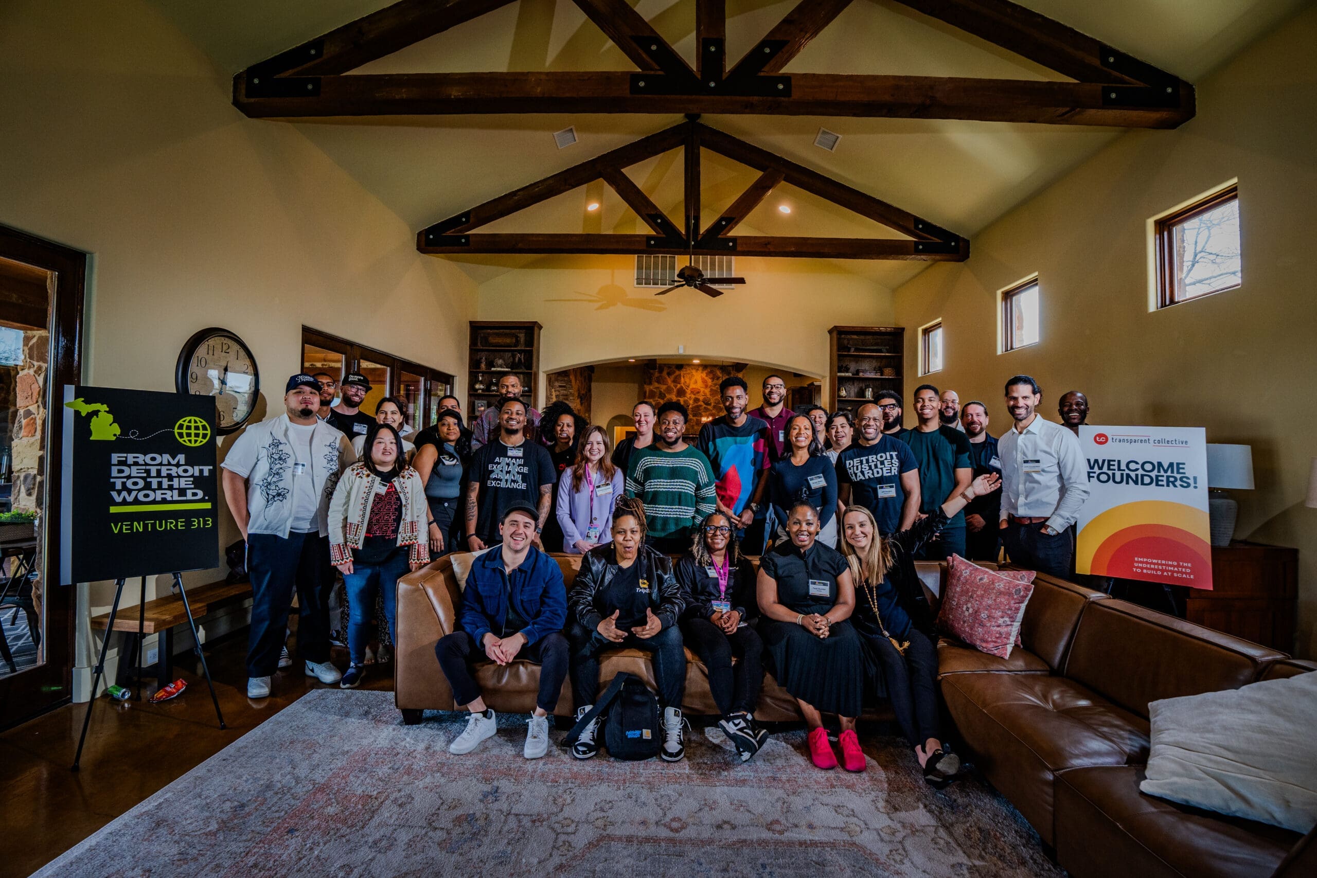 A large group of people sitting on a couch and standing for a photograph