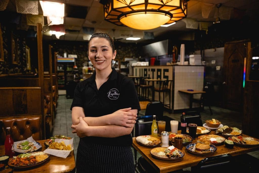 A woman smiles and poses with her arms crossed at her chest